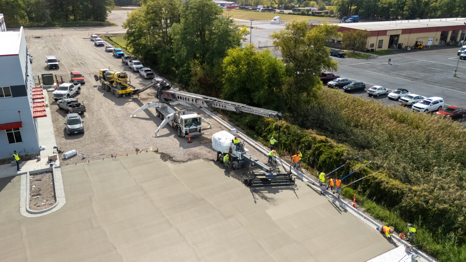 Overhead drone view of a concrete pump truck and crew pouring a new concrete lot at the Rihm Kenworth dealership