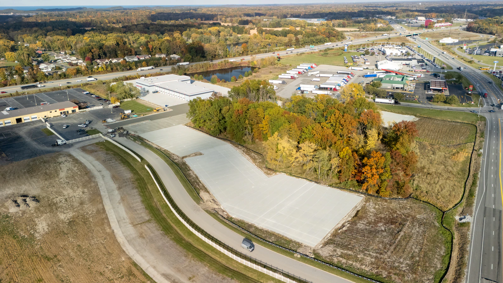 Wide aerial view of the finished Rihm Kenworth dealership lot in fall, showing new concrete paving and sitework