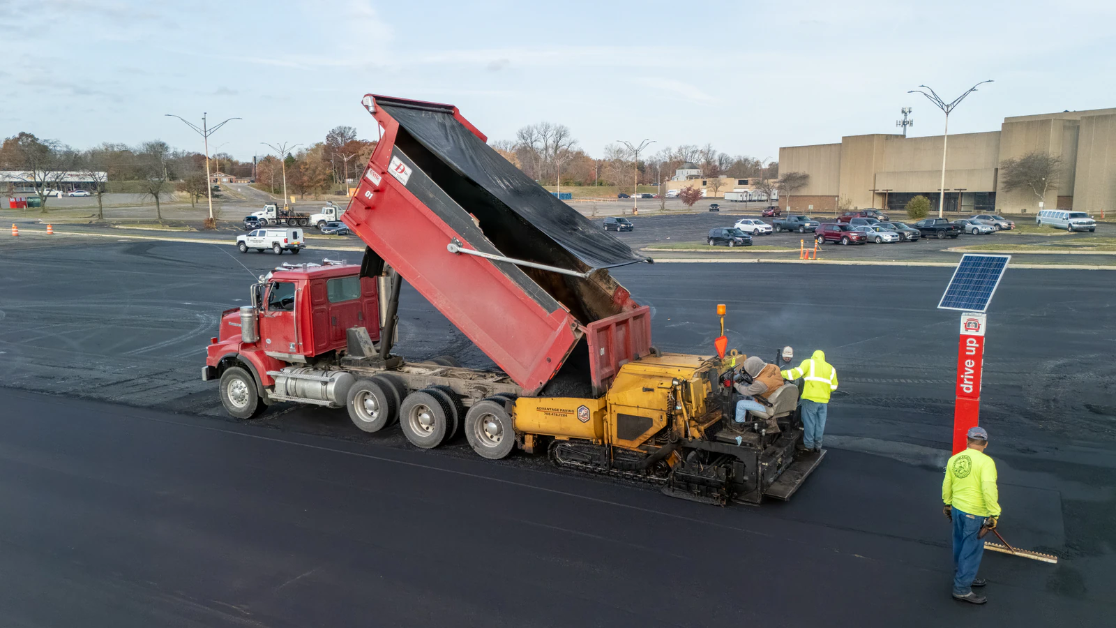 Advantage Paving crew paving a Target store parking lot at dusk with a dump truck and asphalt paver during an emergency repair in Northern Indiana