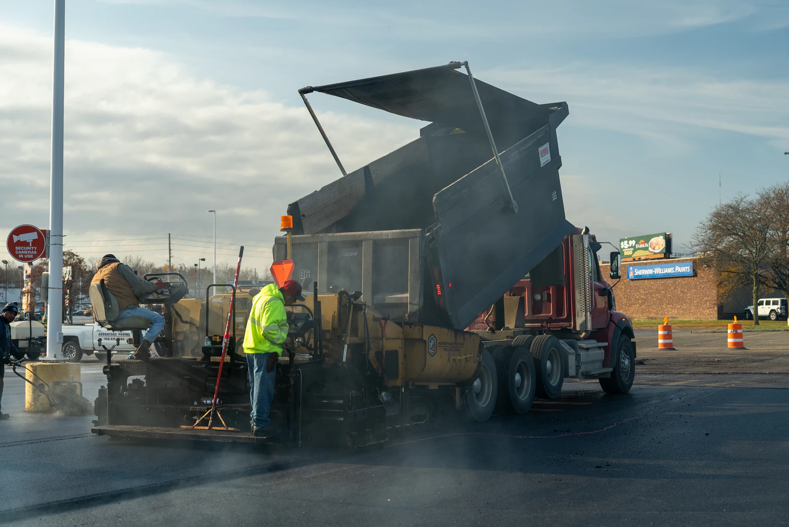 Dump truck unloading hot-mix asphalt into a paver during the Target emergency pavement repair in Northern Indiana